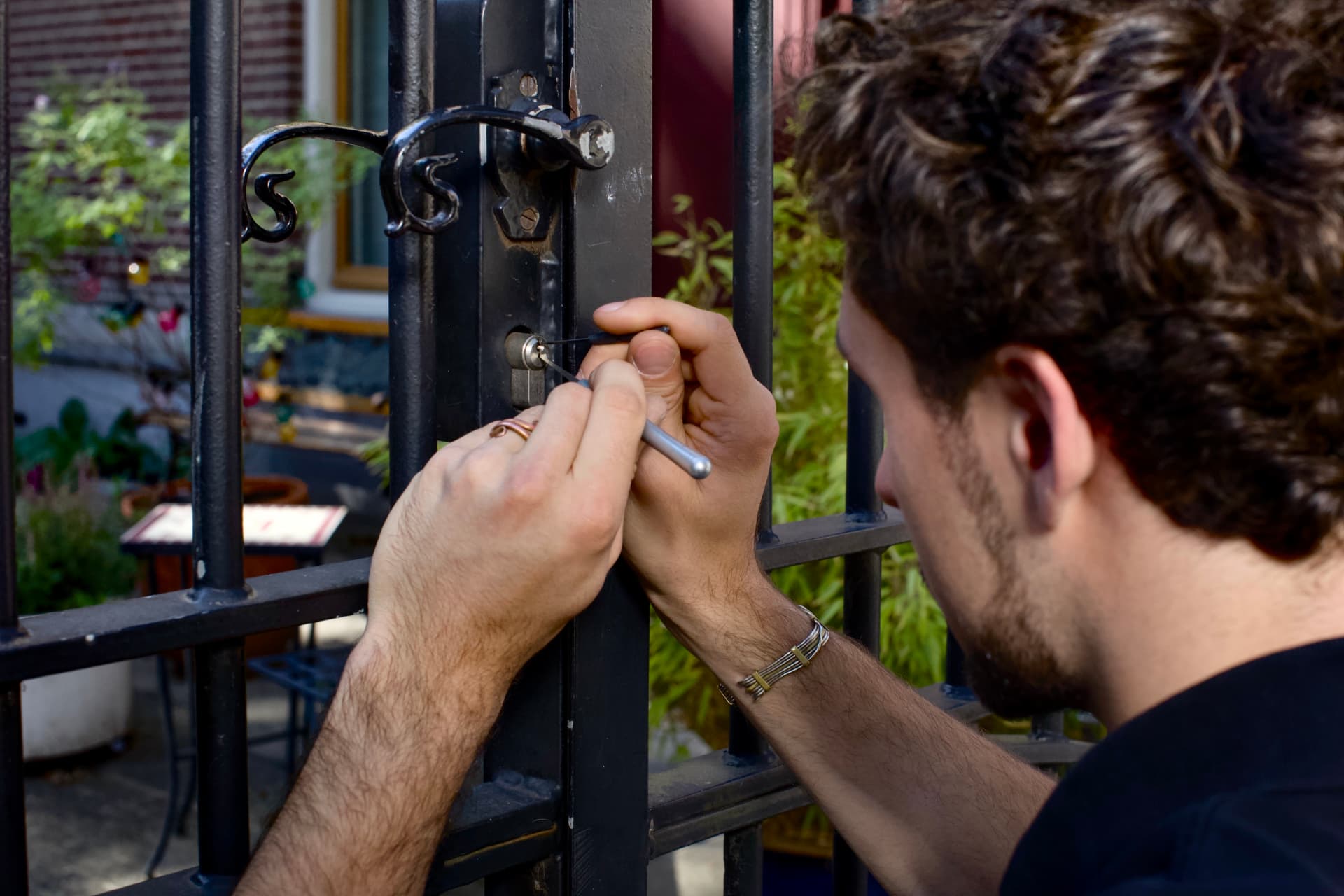 Locksmith picking the lock of a wrought iron gate in Amsterdam